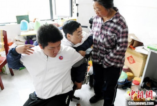 江西省南康中學北校區(qū)的高三學生朱金祥(左)來到學校給鐘華強母子安排的公寓，準備背他去課堂上課。 卓忠偉 攝