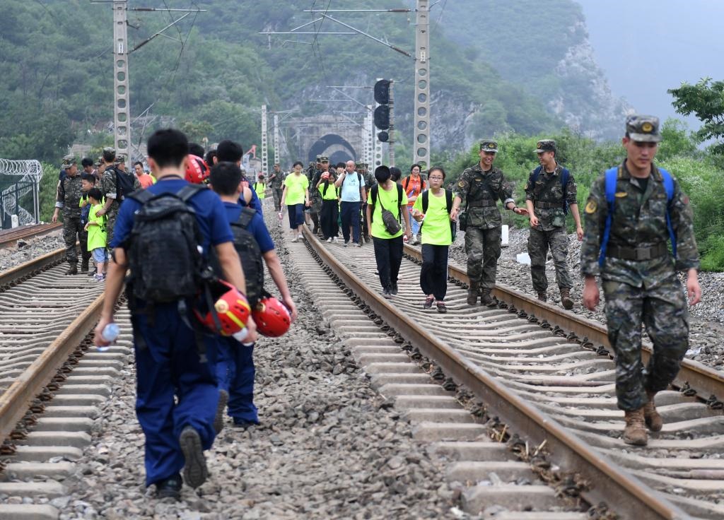 8月2日，部分滯留在北京市門頭溝山區(qū)受困列車的旅客，在救援人員幫助下前往轉(zhuǎn)運客車。新華社記者張晨霖 攝