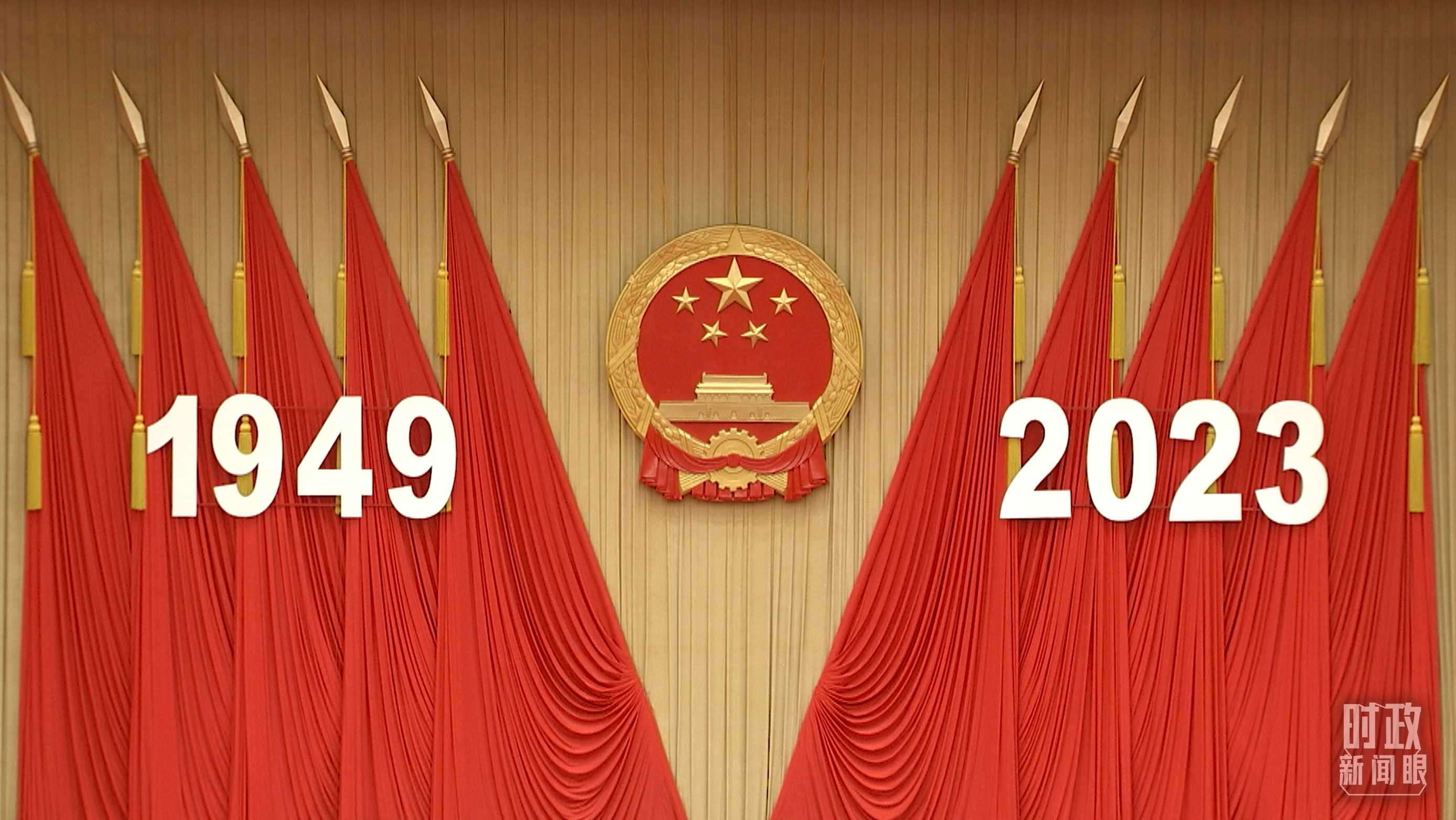 △人民大會(huì)堂宴會(huì)廳內(nèi)，主席臺(tái)上方高懸著莊嚴(yán)的國(guó)徽，“1949－2023”大字年號(hào)在鮮艷的紅旗映襯下格外醒目。