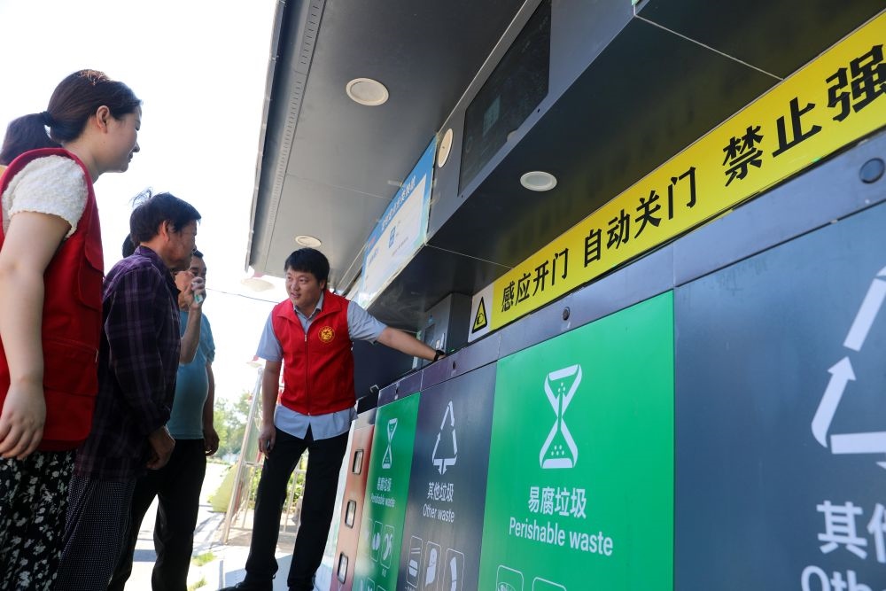 在安徽省合肥市長豐縣莊墓鎮(zhèn)棗林社區(qū)，志愿者指導(dǎo)居民使用智能垃圾分類回收設(shè)備（2023年9月1日攝）。新華社記者 曹力 攝