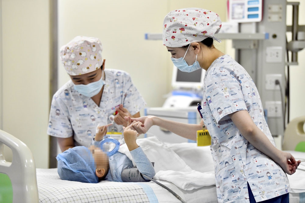 在山東省棗莊市婦幼保健院兒童ICU病房，醫(yī)護人員為完成靶向治療藥物諾西那生鈉的4歲脊髓性肌萎縮癥患兒加油鼓勁（2022年1月1日攝）。諾西那生鈉注射液是我國首個獲批治療脊髓性肌萎縮癥的進口藥物，2019年進入中國市場時，每針價格近70萬元。在2021年國家醫(yī)保目錄藥品談判中，以3.3萬元每針的價格進入新版醫(yī)保藥品目錄。新華社記者 郭緒雷 攝