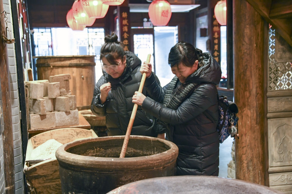 游客在平遙古城東湖老醋坊內(nèi)體驗陳醋發(fā)酵打耙（2022年1月28日攝）。新華社發(fā)（梁生仁攝）