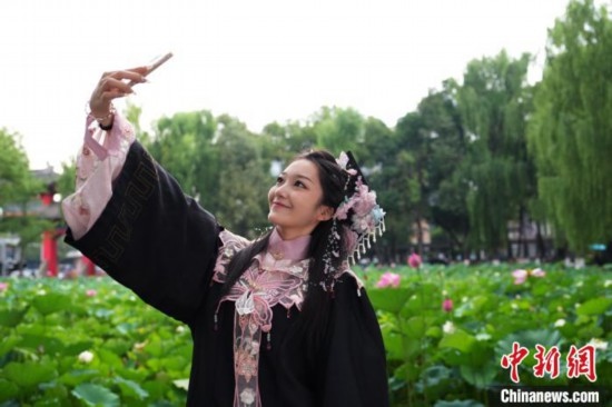 6月19日，時(shí)值一年畢業(yè)季，四川大學(xué)望江校區(qū)荷花池里的荷花盛開，成為了畢業(yè)生們的打卡圣地，吸引了眾多畢業(yè)生拍照留念。圖為畢業(yè)生在荷花池邊拍照留念。中新社記者 安源 攝