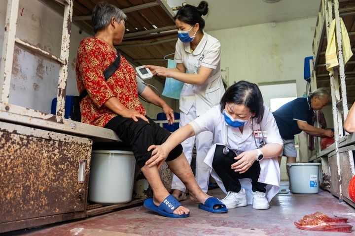 2024年7月30日，在湖南省湘潭縣河口中學(xué)安置點(diǎn)，醫(yī)務(wù)人員為受洪水影響而轉(zhuǎn)移安置的群眾檢查身體。 新華社記者 陳思汗 攝