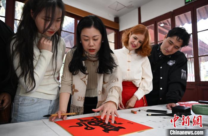 1月20日，西泠印社社員李硯（左二）為外籍留學(xué)生講述蛇年福字貼創(chuàng)作靈感。當(dāng)日，來自巴西、馬來西亞、加納、哈薩克斯坦的外籍留學(xué)生在浙江杭州西泠印社體驗福貼、春聯(lián)和篆刻，感受古老的中國傳統(tǒng)文化。中新社記者 王剛 攝